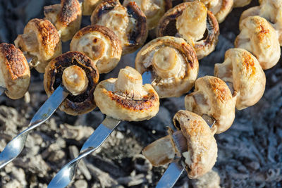 Mushrooms fried on skewers, arranged in a row on the grill.