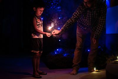 Young couple looking at illuminated camera at night