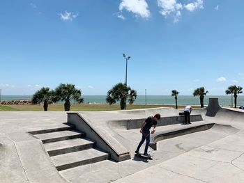 Side view of man walking on staircase against sky