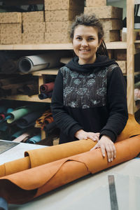 Tailor woman with fabric rolls. pretty brunette designer looking camera while holding pile of