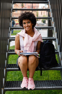 Portrait of smiling young woman sitting on staircase