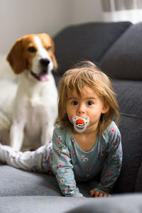 Portrait of cute girl with dog on sofa