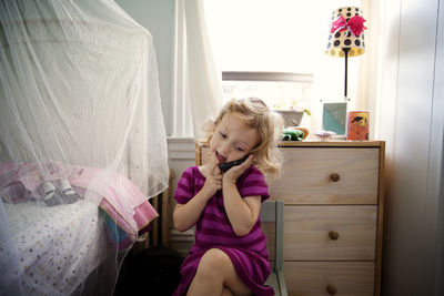 Playful girl using mobile phone while playing at home