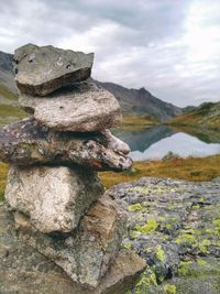 Stack of rocks by lake against sky