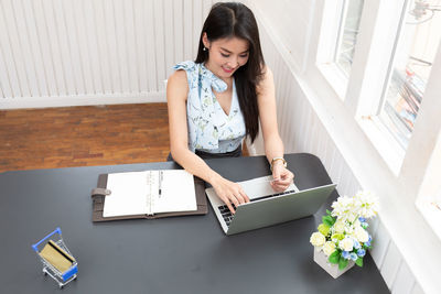 High angle view of woman using phone on table
