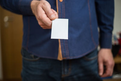 Midsection of man holding paper