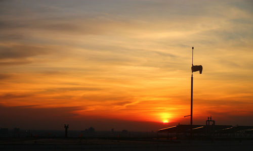 Silhouette street against orange sky during sunset