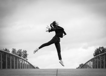 Low angle view of woman jumping on bridge