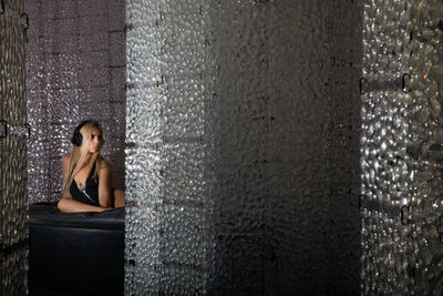 Woman listening music while sitting against wall