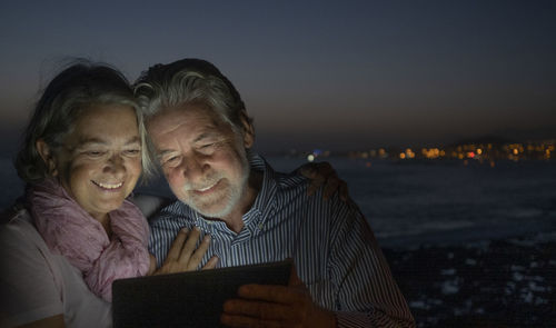 Rear view of couple on beach against sky at night