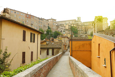 Footpath amidst buildings in town against clear sky