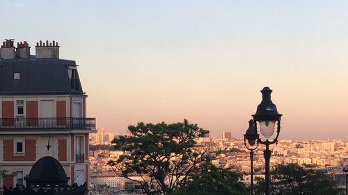 Street light by building against sky at sunset