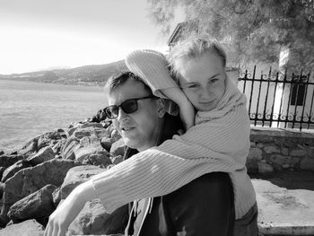 Portrait of mother and daughter on beach against sky