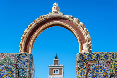 Low angle view of arch and mural against clear blue sky