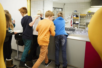 Children putting plates in crate after having lunch at school cafeteria