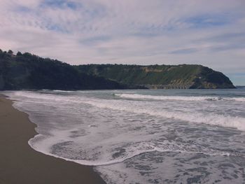 Scenic view of beach against cloudy sky