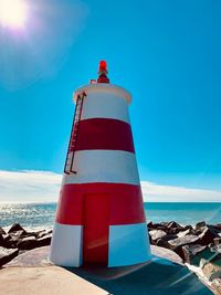 Lighthouse by sea against sky