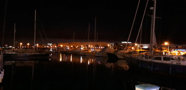 Sailboats moored in harbor at night