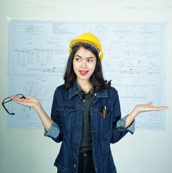 Portrait of beautiful young woman standing against wall