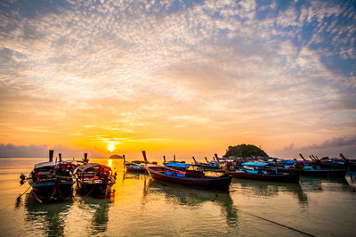 Boats moored in marina at sunset