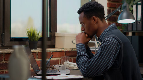 Side view of young man using mobile phone in cafe