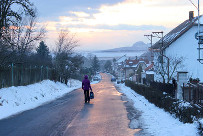 Rear view of woman walking on road in winter