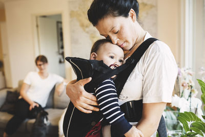 Mother carrying daughter in baby carriage at home