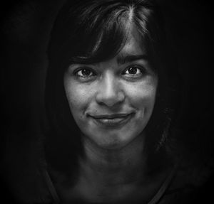 Close-up portrait of woman against black background