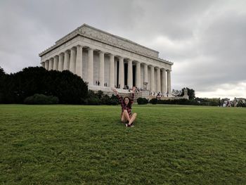 Woman in front of building against cloudy sky