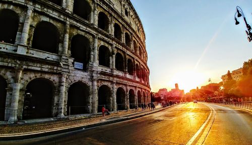 Road passing through city during sunset