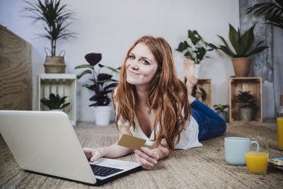 Portrait of young woman using phone while sitting on table