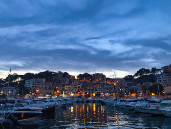 Sailboats moored at harbor in city against sky