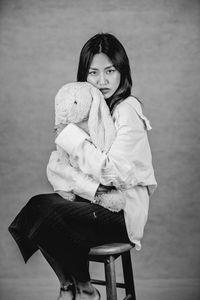 Emotional portrait of woman sitting on chair with stuffed toy