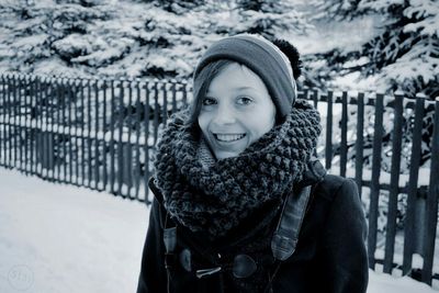 Portrait of smiling young woman standing in snow