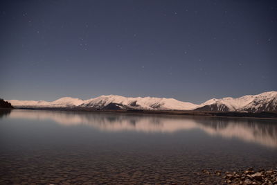 Scenic view of lake and mountains against sky at night