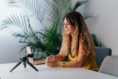 Young woman using phone while sitting on table