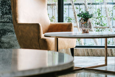 Empty chairs and table by potted plants