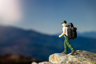 Side view of man standing on rock by sea against sky