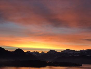 Scenic view of silhouette mountains against dramatic sky during sunset