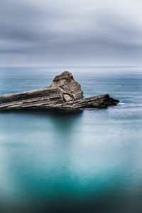 Rock formation in sea against sky