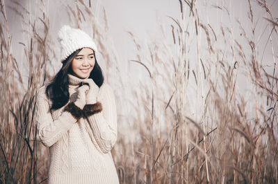 Young woman in warm clothing standing amidst plants on field