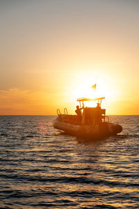 Small fishing boat with two fishermen on board in silhouette light at sunset. seascape at sunset