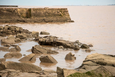 Rock formation on beach against sky