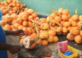 Cropped image of vendor chopping coconut at market stall