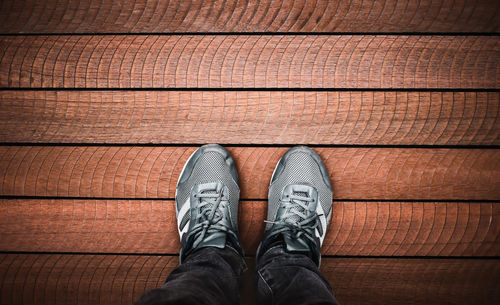 Low section of man standing on hardwood floor