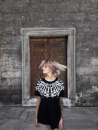 Full length of young woman standing against wall