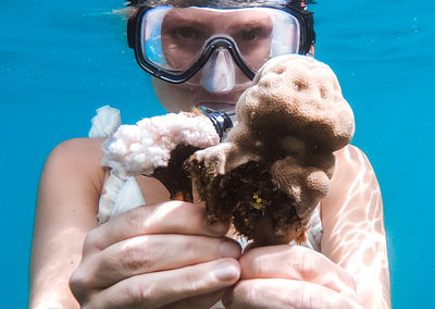 Portrait of woman holding coral in sea