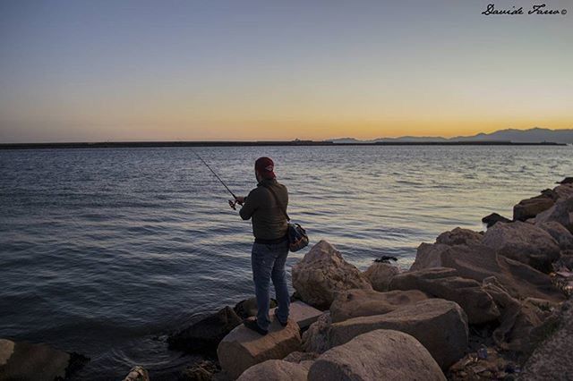 water, sea, lifestyles, scenics, tranquil scene, clear sky, tranquility, leisure activity, beauty in nature, standing, sunset, rear view, rock - object, copy space, nature, full length, horizon over water, idyllic