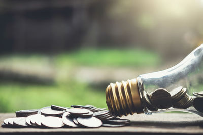 Close-up of coins spilling out of light bulb on table