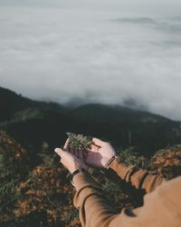 Midsection of person holding umbrella against mountain range
